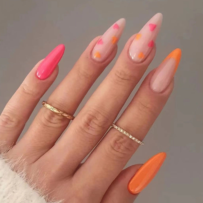 Long pink and orange press on nails with heart accents and orange French tips