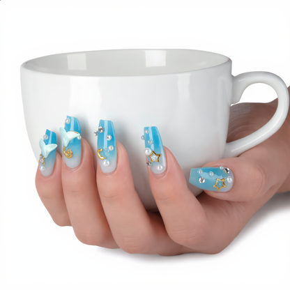 Blue ombre press on nails with celestial charms styled with a white coffee cup