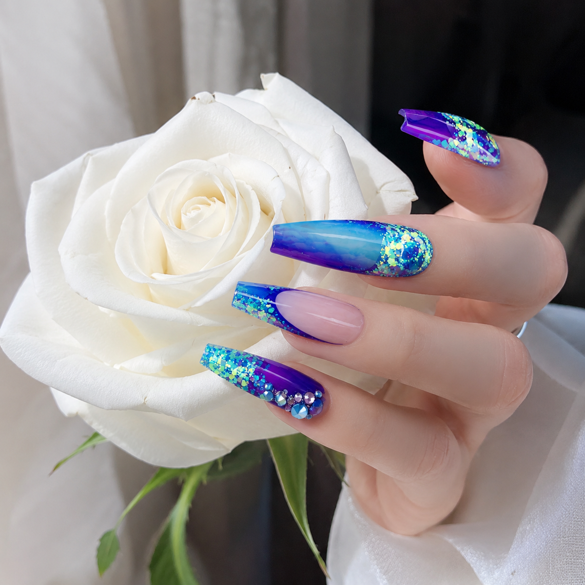 Blue purple glitter press on nails worn on hand holding a white rose