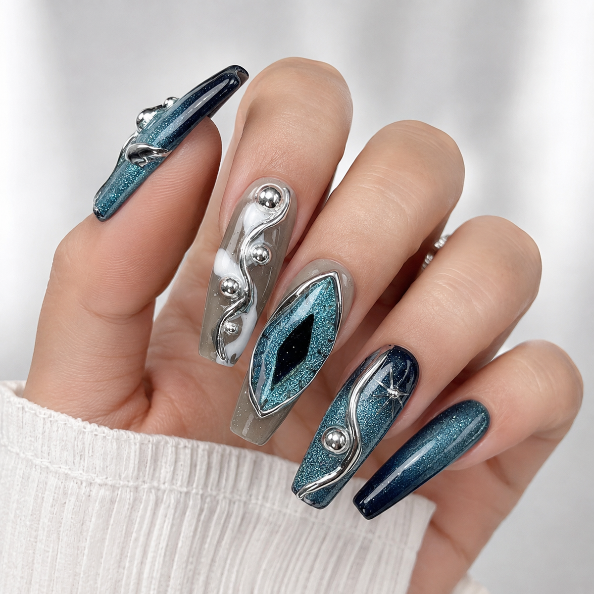 Blue teal cat eye chrome 3D press on nails with metallic silver accents on hand, luxury handmade reusable fake nails, white background.