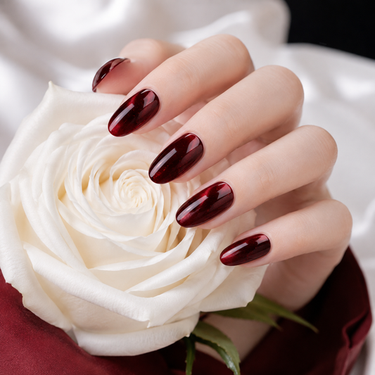 Burgundy red cat eye press on nails with glossy shimmer holding a white rose