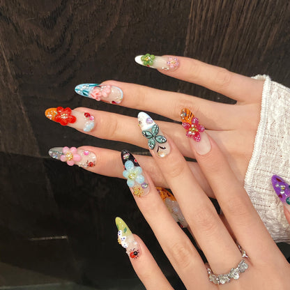 Colorful 3D press on nails worn on both hands with floral and butterfly charms