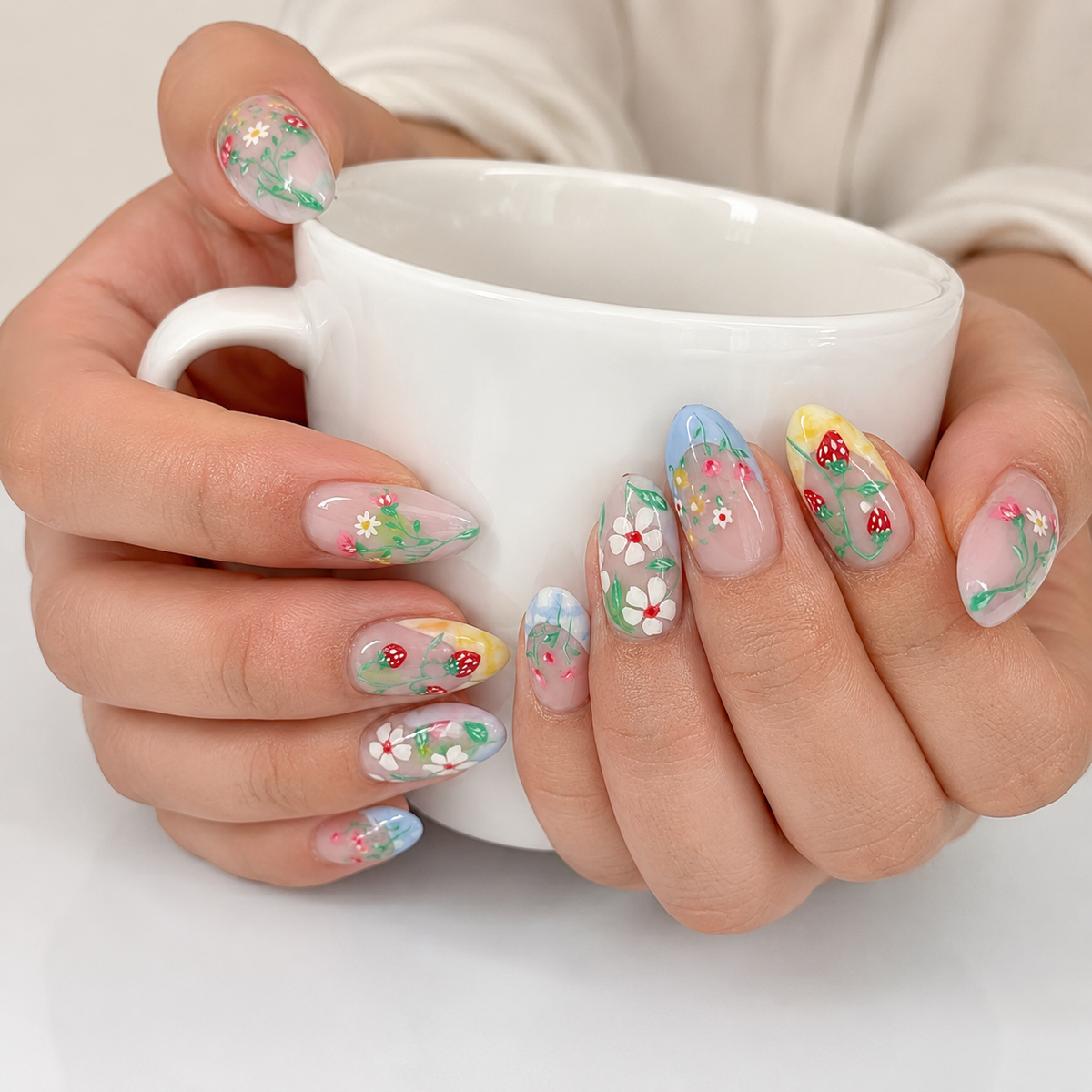 Floral strawberry press on nails on hand holding a white coffee cup
