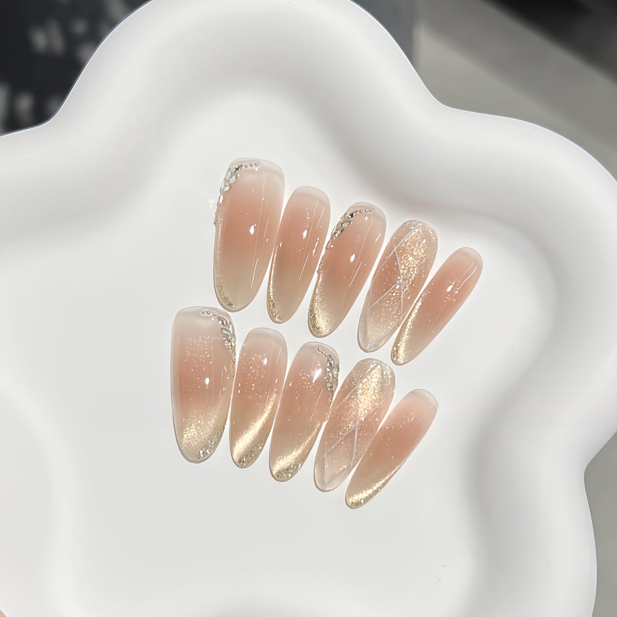 Full set of champagne press on nails with nude shimmer, gold glitter and crystal details