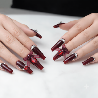 Long burgundy press on nails with crystal rhinestones displayed on both hands