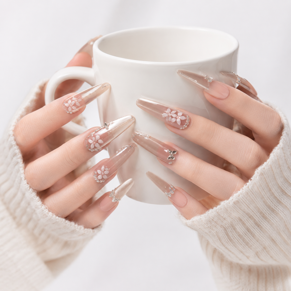 Luxury nude floral press on nails with silver details holding a white coffee cup