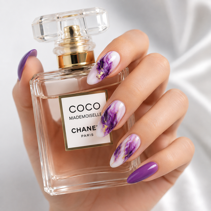 Luxury purple marble press on nails with gold accents holding a perfume bottle