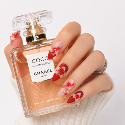 Luxury red floral almond press on nails holding a premium perfume bottle, handcrafted 3D flower fake nails with glossy reusable salon-quality finish.