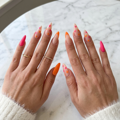 Pink orange almond press on nails displayed on both hands over white marble