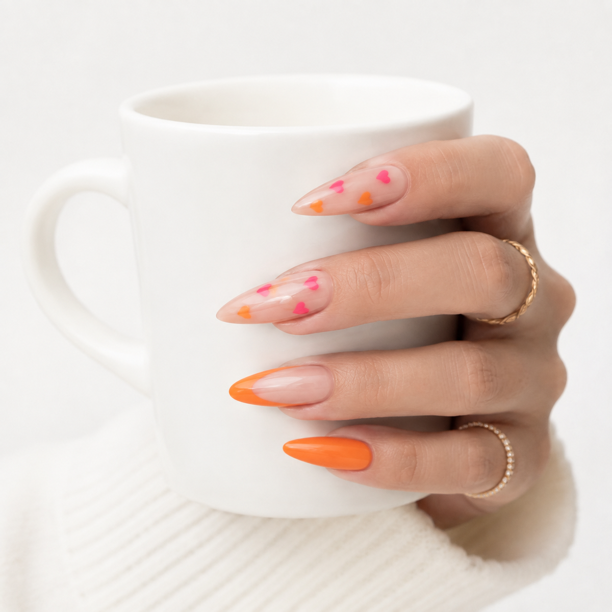 Pink orange heart press on nails worn on hand holding a white coffee cup