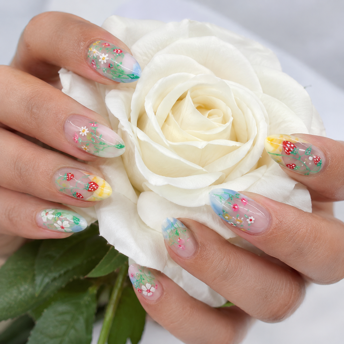 Spring floral press on nails on hand holding a white rose