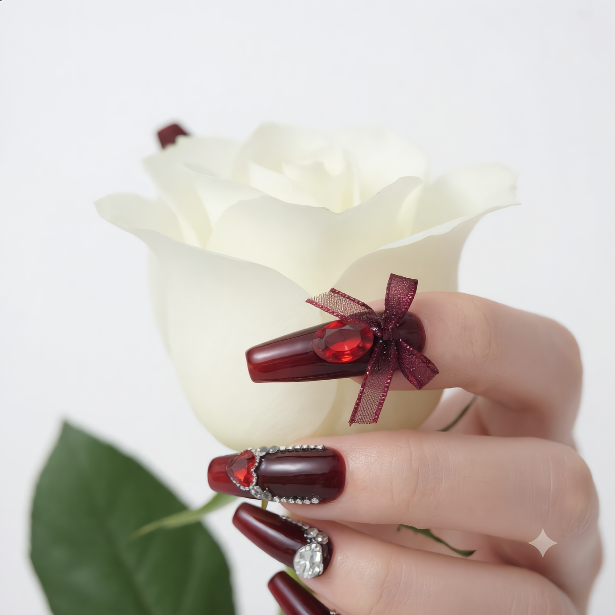 Wine red press on nails with crystal rhinestones and bow holding a white rose
