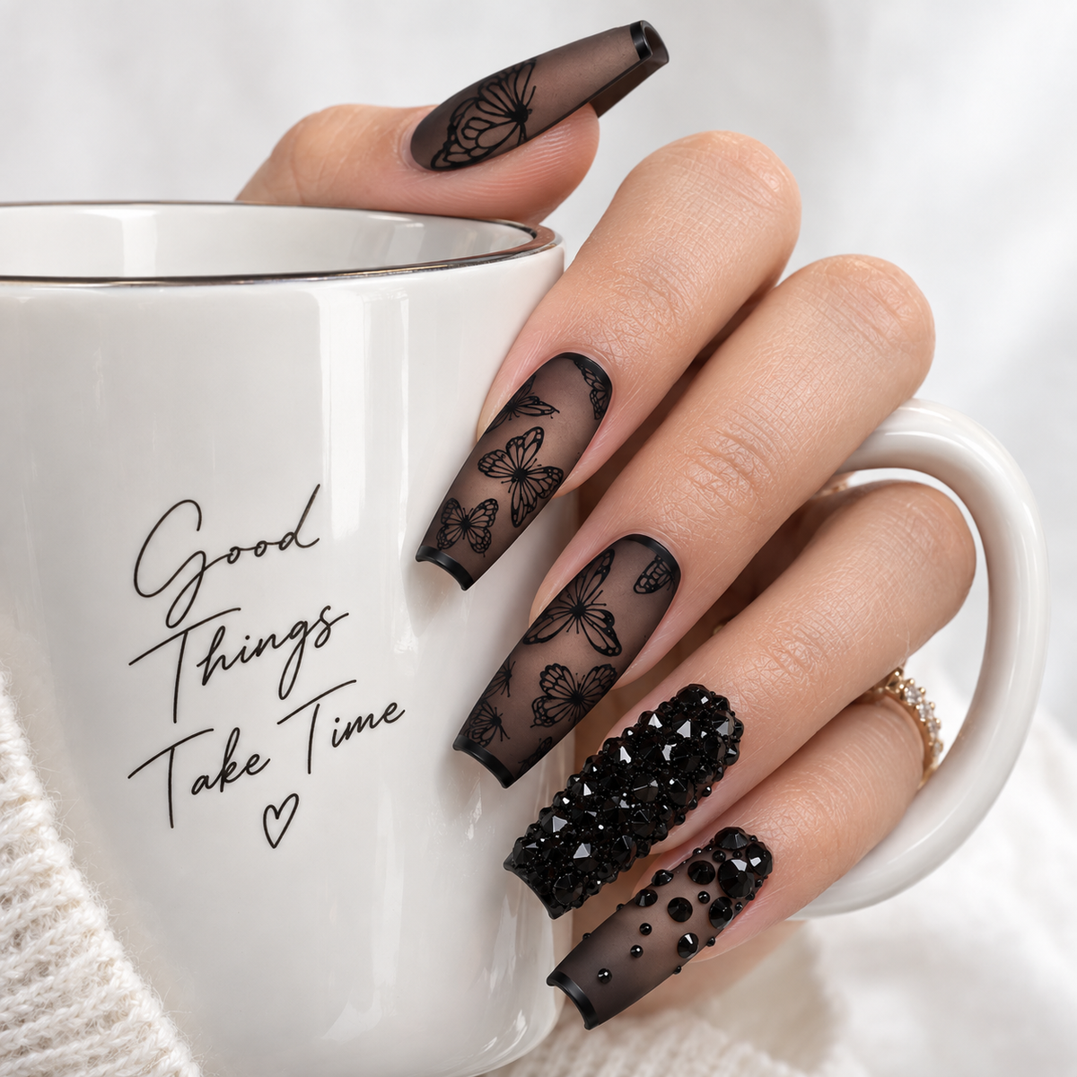 Long black butterfly press-on nails with crystal rhinestones in an elegant lifestyle setting
