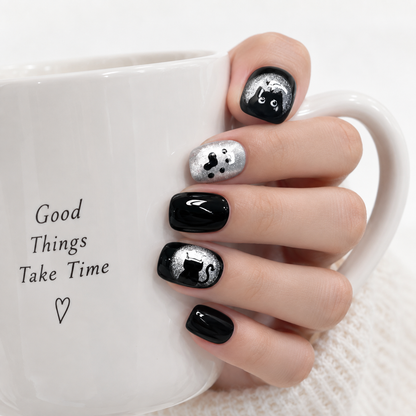 Black and silver cat press-on nails styled with a white coffee cup