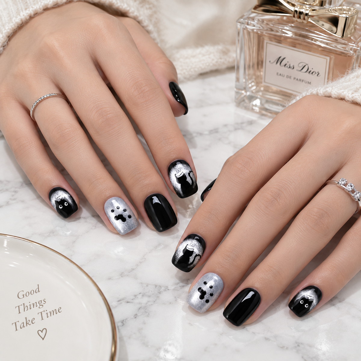 Glossy black and silver cat press-on nails with paw print nail art