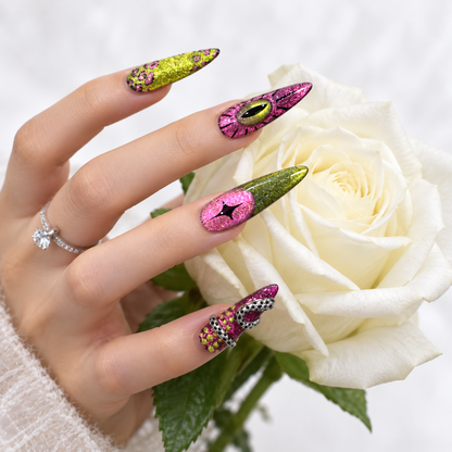 Pink and green glitter stiletto press-on nails with eye designs and metallic 3D details