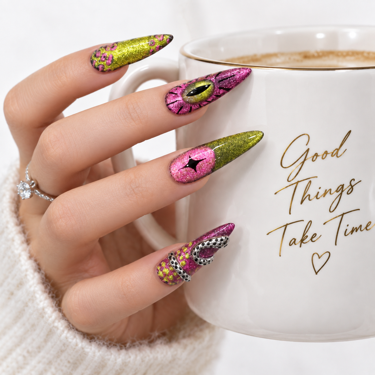 Long pink and green press-on nails with glitter eye nail art styled with a white coffee cup
