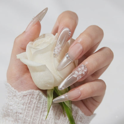 Luxury 3D floral press on nails with nude shimmer design holding a white rose