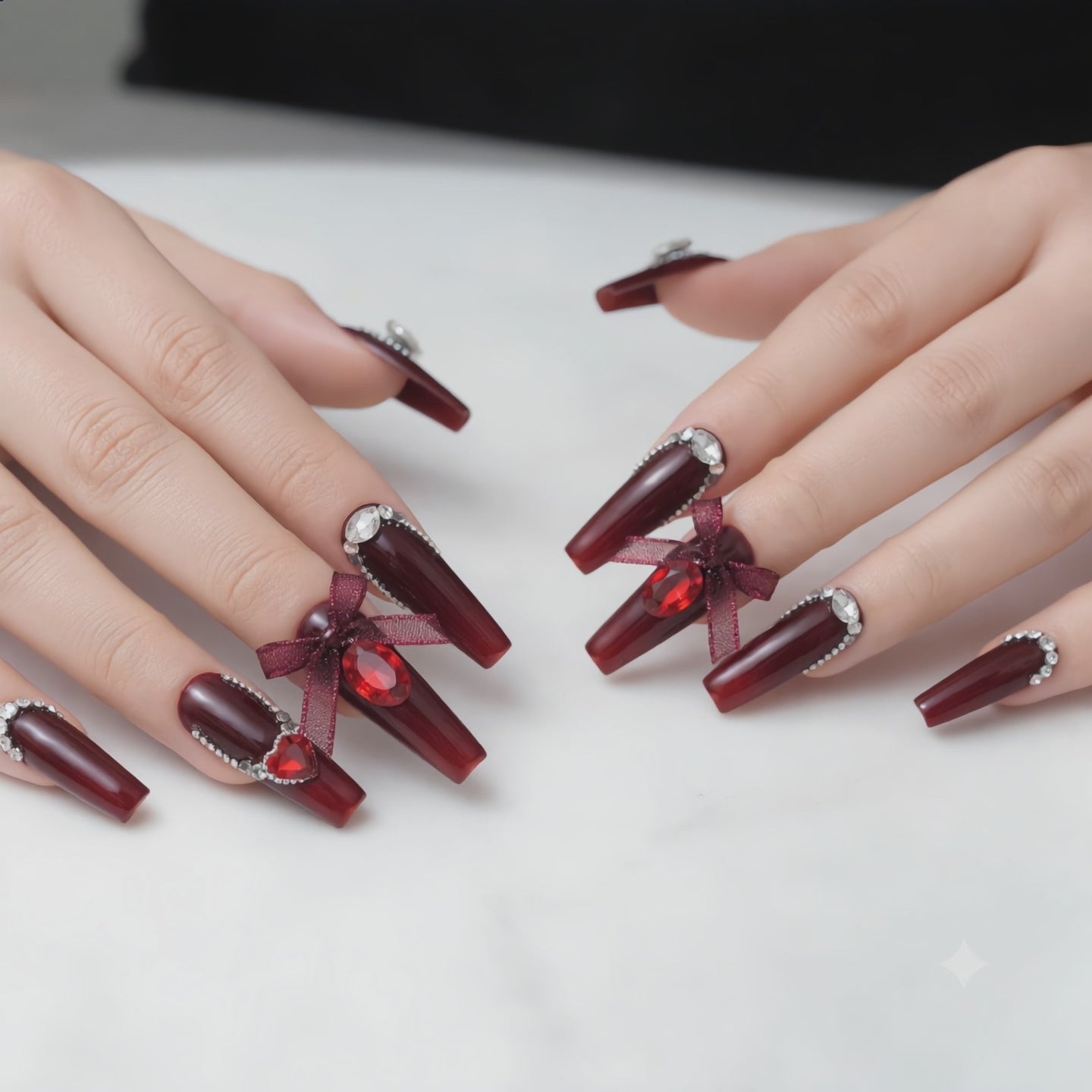 Long burgundy press on nails with crystal rhinestones displayed on both hands