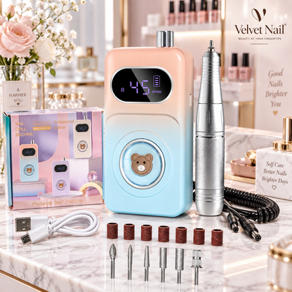 Velvet Nail professional portable nail drill machine in pink and blue gradient, complete premium e-file kit with product packaging box, silver handpiece, charging cable, and diamond drill bits set on white marble table.
